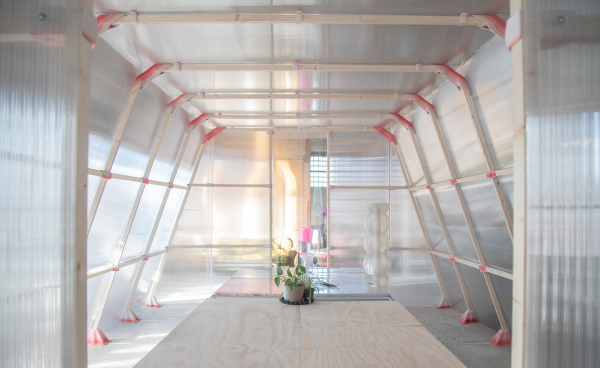 Pavilhao arquitetonico translúcido montado com modulos impressos em 3D, dentro de galpao